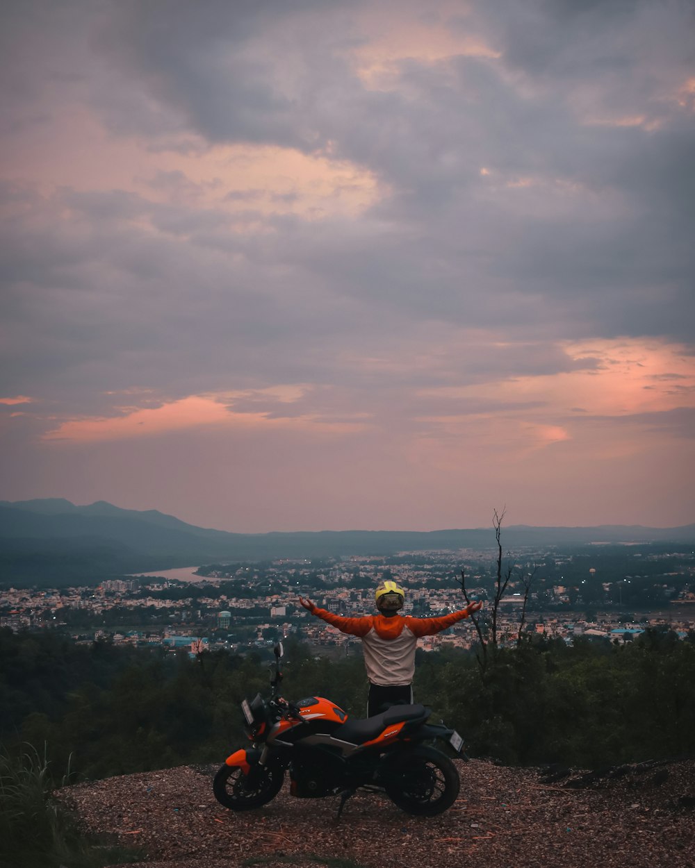 a man sitting on top of a motorcycle on top of a hill