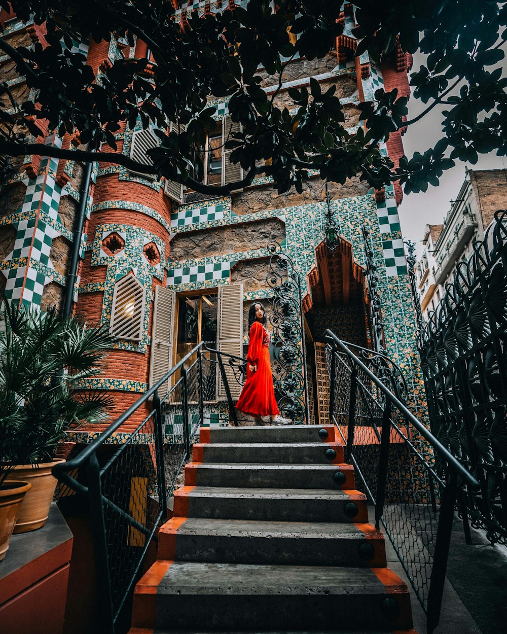 a woman in a red dress is walking down a set of stairs