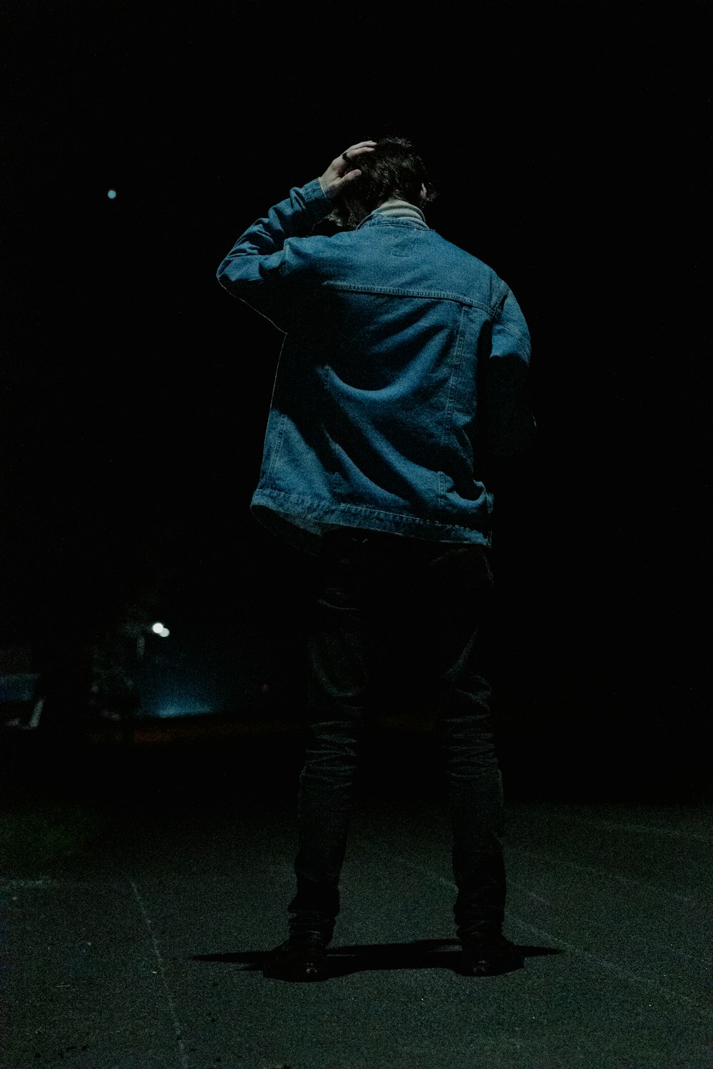 a man standing in the dark with his hands on his head