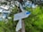 A wooden post with multiple directional signs is situated in a forest area. The signs are in both Ukrainian and English, displaying distances and estimated times to various destinations in a mountainous region. Surrounding the post are lush green trees and foliage.