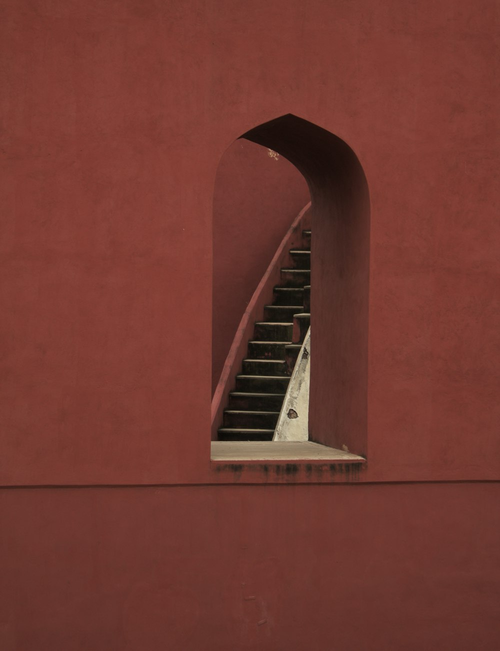 a red wall with a staircase going up it