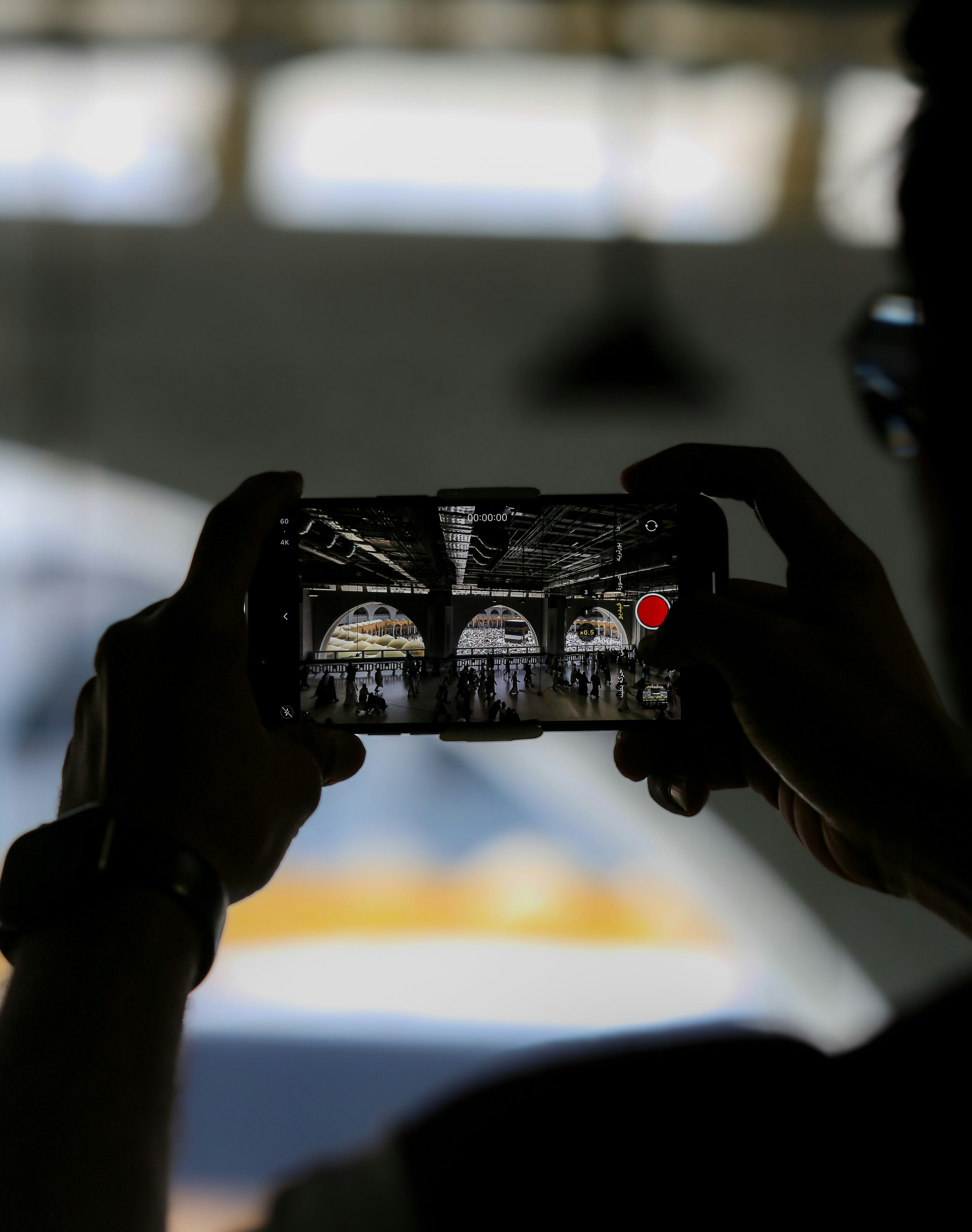 Person filming with a smartphone inside a building.
