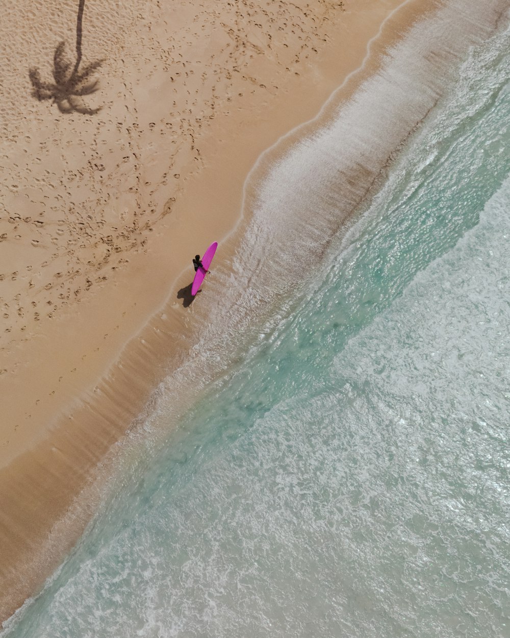 an aerial view of a person on a beach with a surfboard
