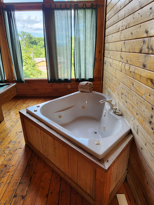 The inviting VVIP massage room featuring a luxurious jacuzzi bathtub surrounded by elegant wood paneling.