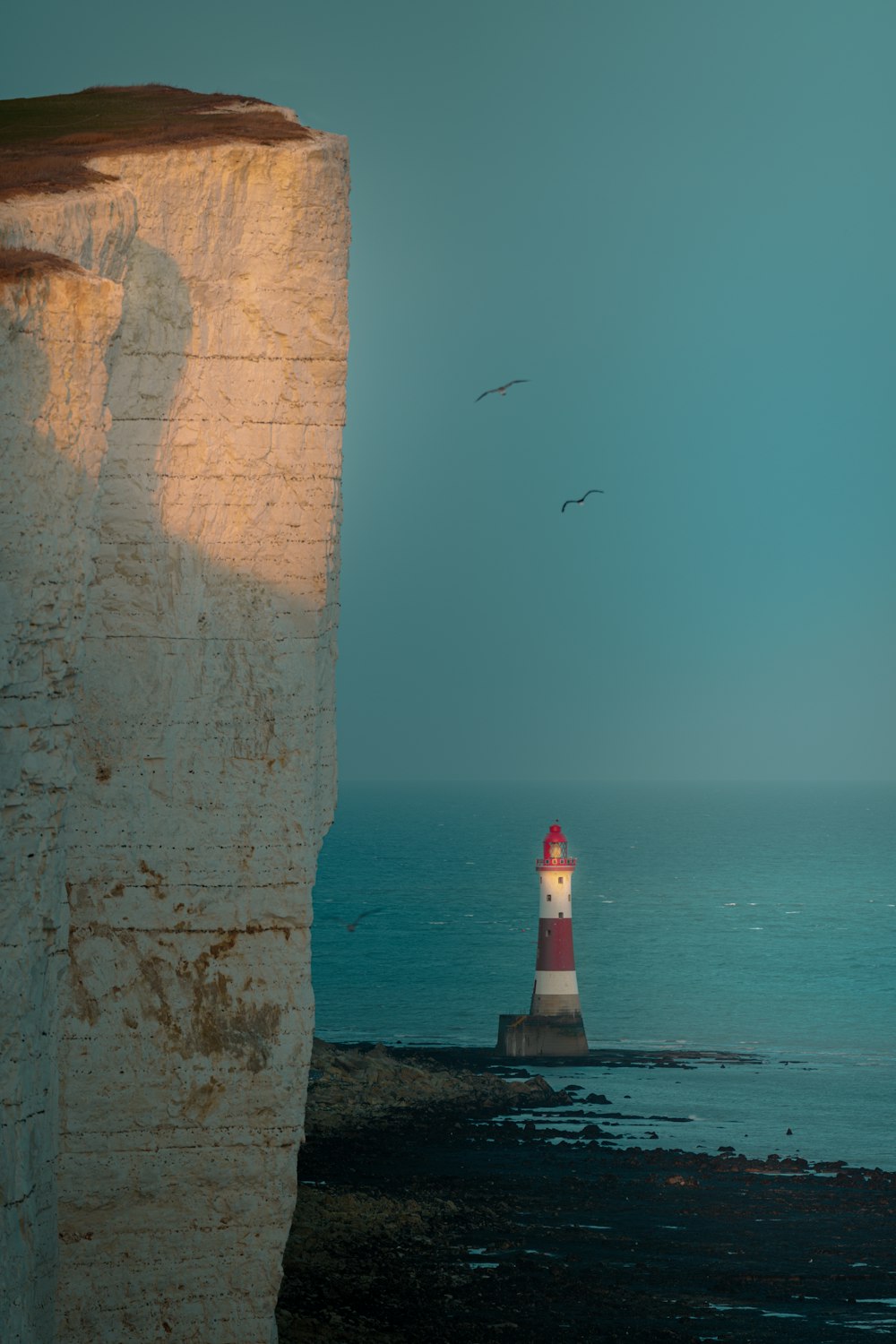 a red and white light house sitting on top of a cliff