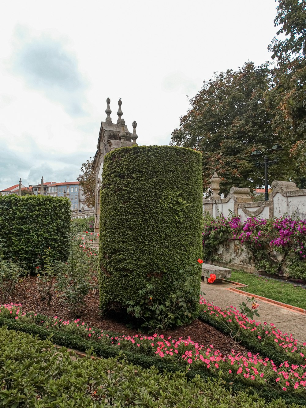 a garden with flowers and a statue in the middle of it