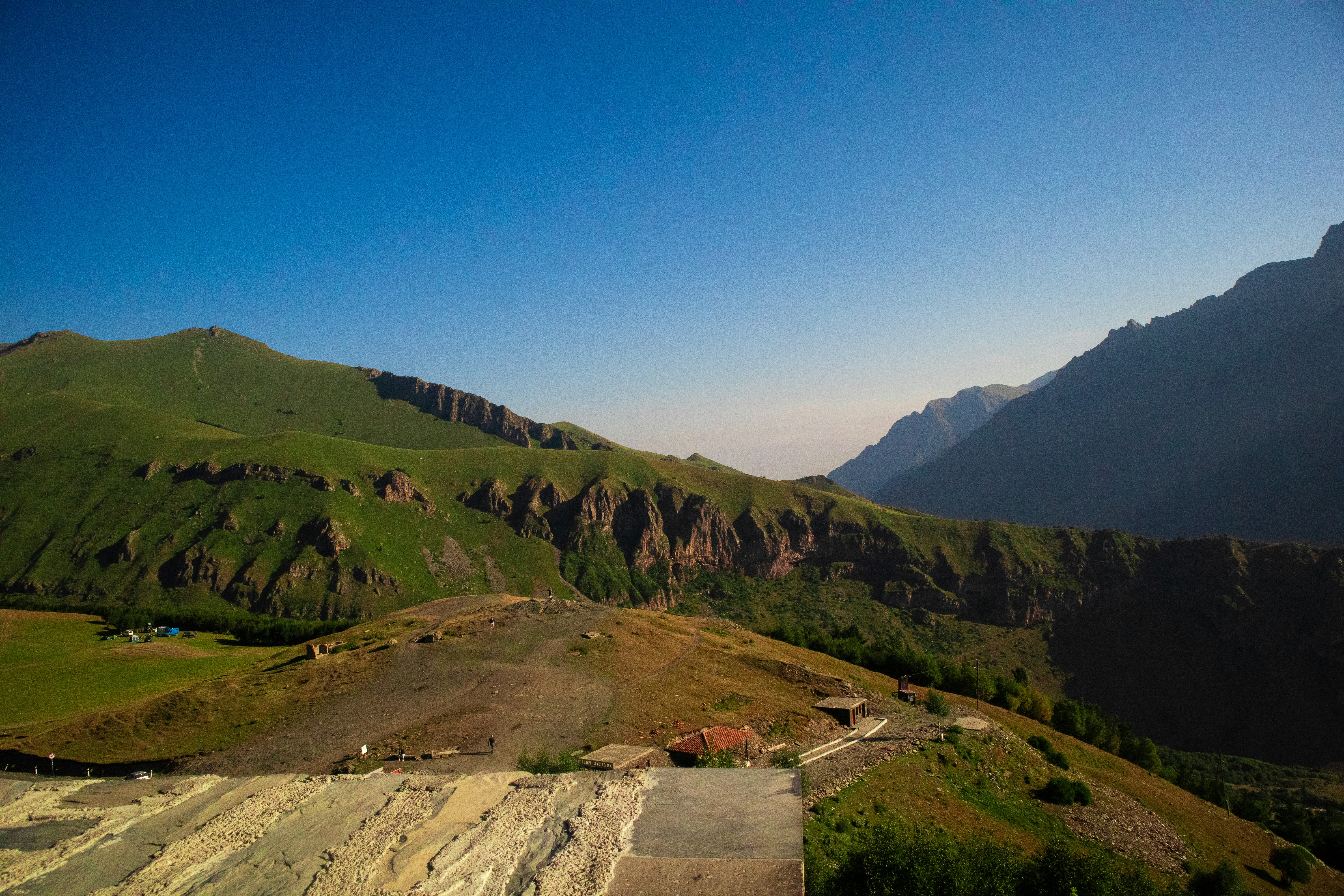 a scenic view of a valley with mountains in the background, A landscape view from Gergeti Trinity church