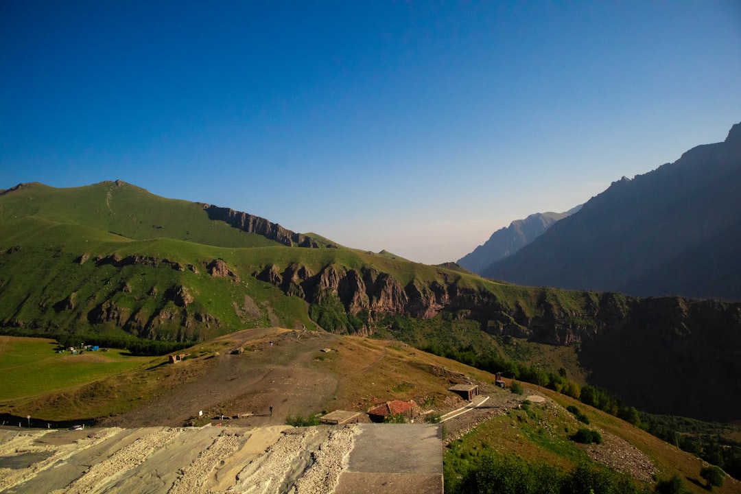 a scenic view of a valley with mountains in the background, A landscape view from Gergeti Trinity church