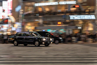 A taxi driving through the vibrant streets of Manchester at dusk.