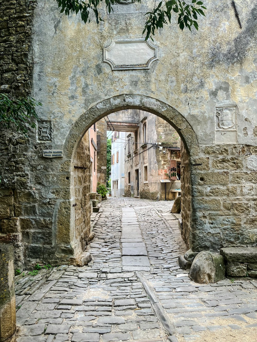 a narrow cobblestone street with a stone archway