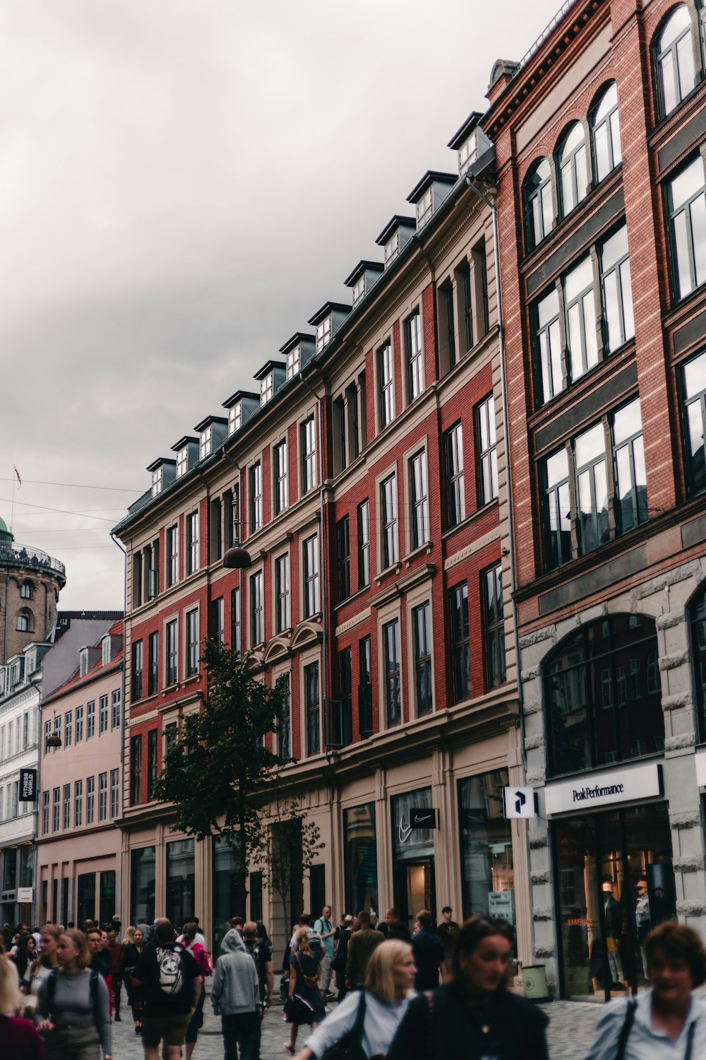 a group of people walking down a street next to tall buildings