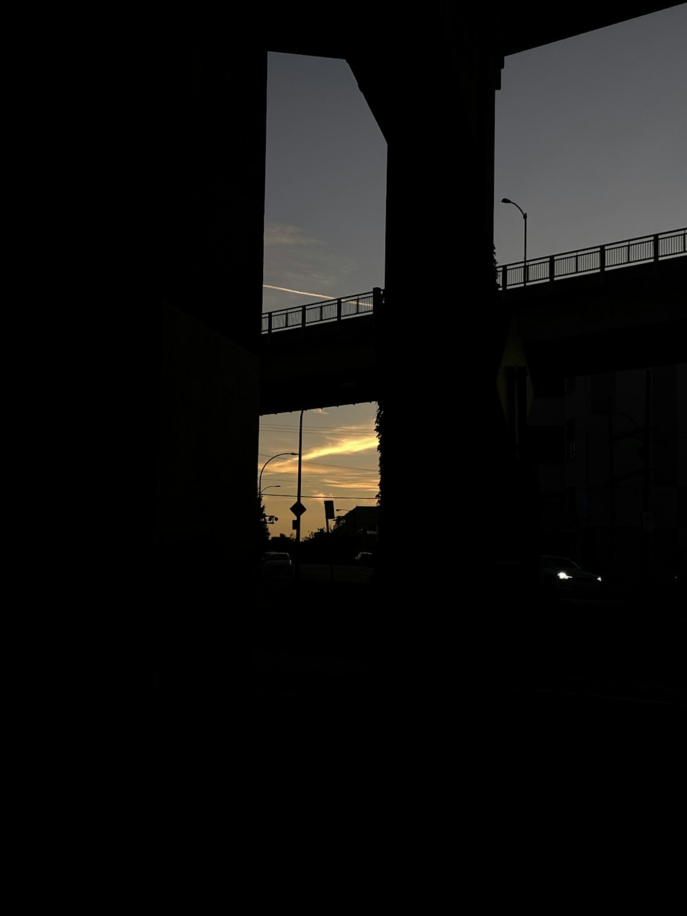 a view of a bridge from a window at sunset