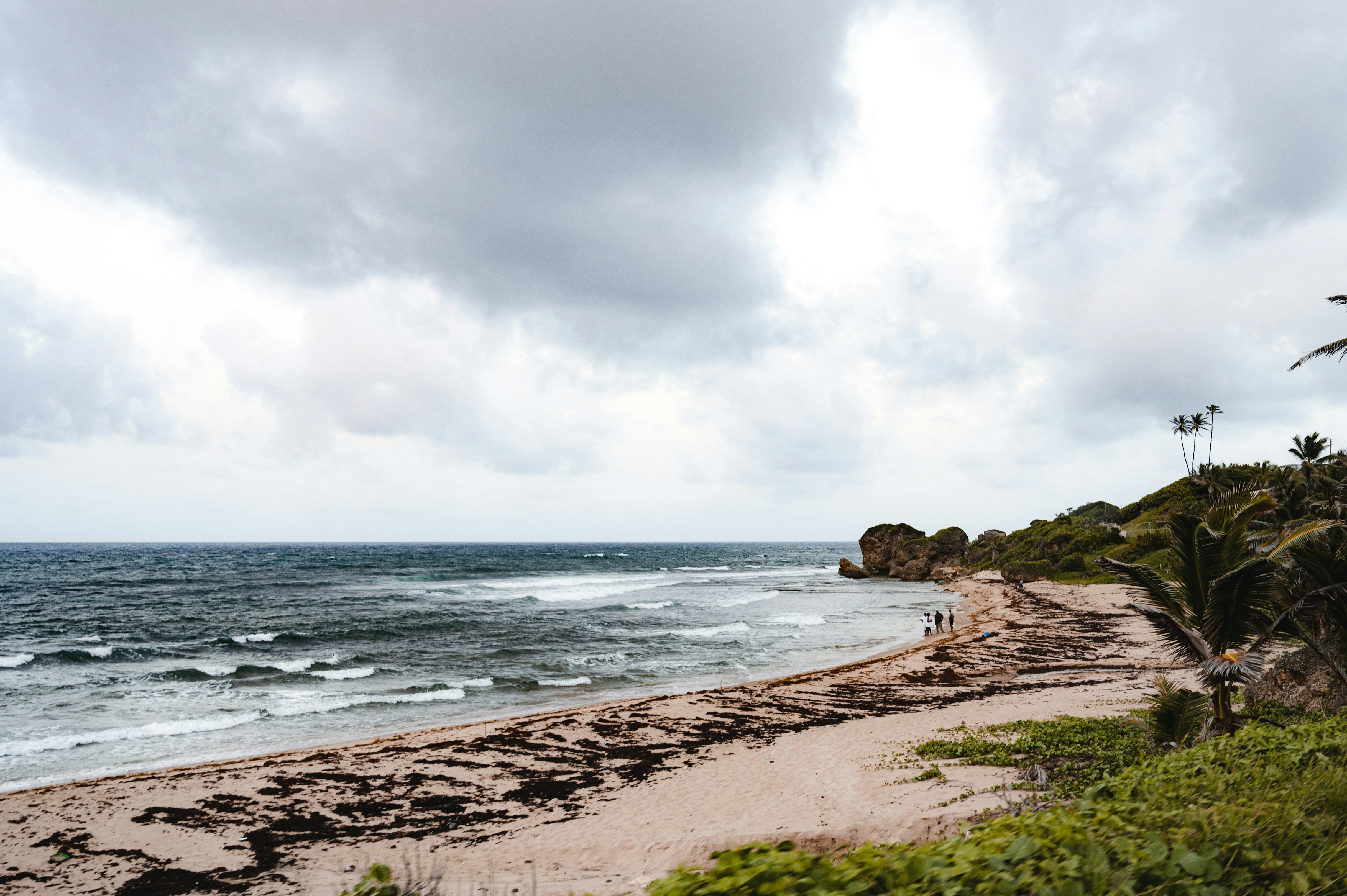 a sandy beach next to the ocean under a cloudy sky