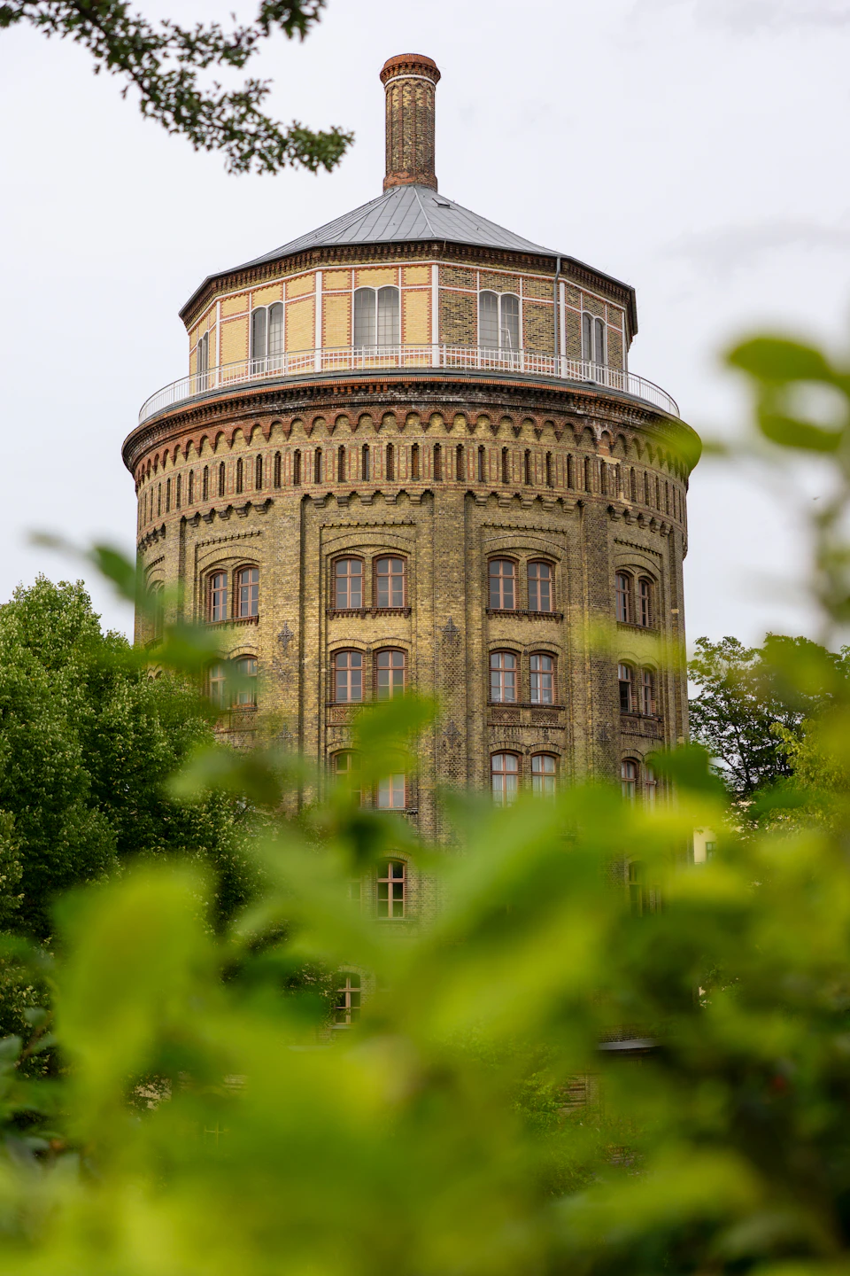 Large, multi-level building with distinctive dome and tower, surrounded by trees in landscape