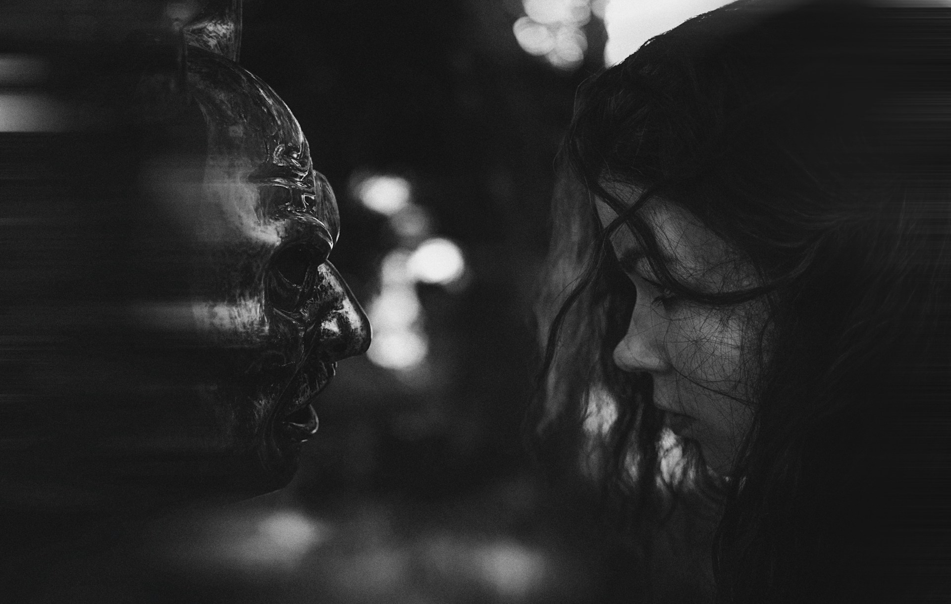 a black and white photo of a woman looking at a statue