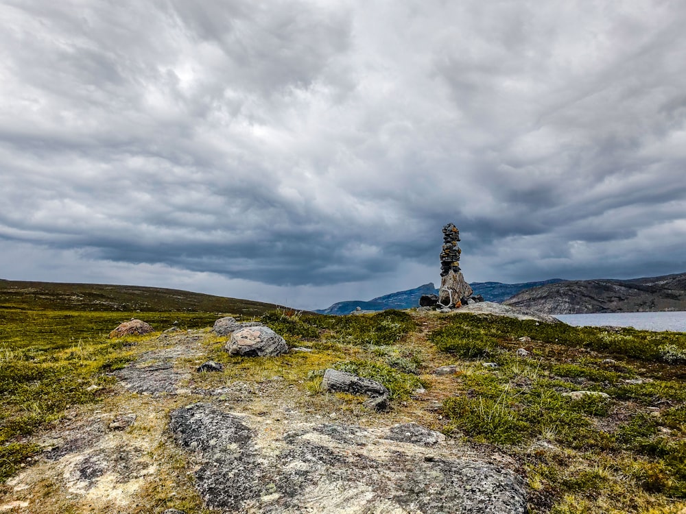 a rock tower sitting on top of a lush green hillside