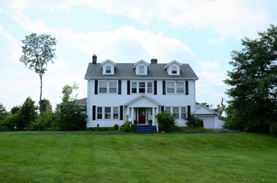 A two-story colonial house surrounded by mature trees in a peaceful neighborhood.