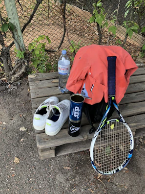 Finished tennis racket displayed on a wooden table with stringing tools nearby.
