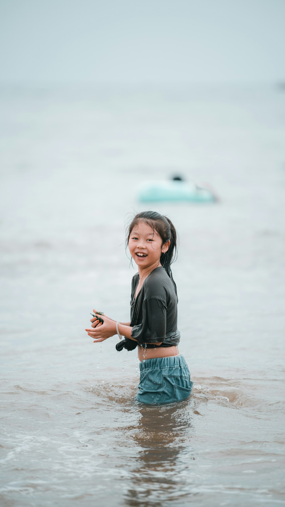 a little girl standing in the water with a frisbee