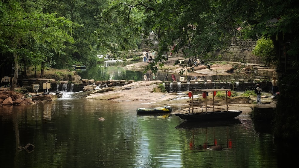 a boat floating on top of a river next to a lush green forest