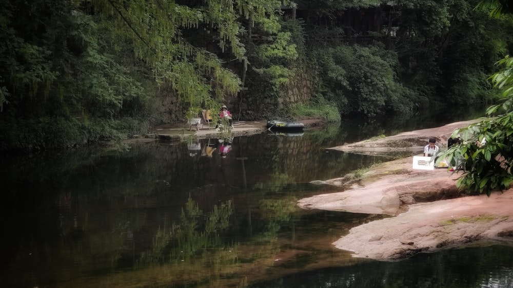 a couple of people standing on the shore of a river