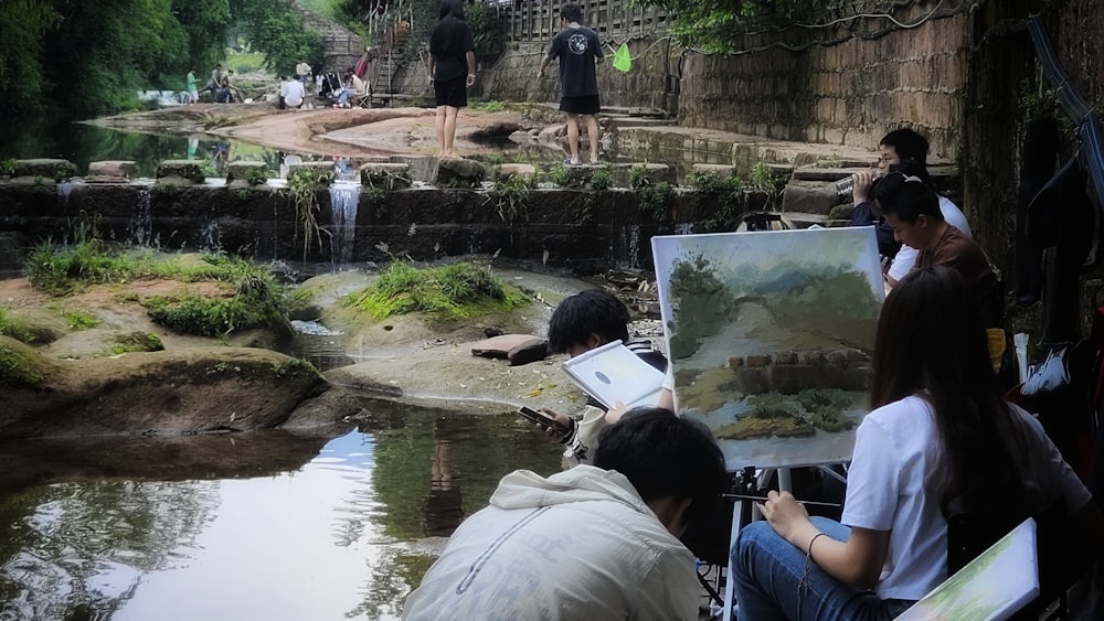 a group of people sitting next to a river