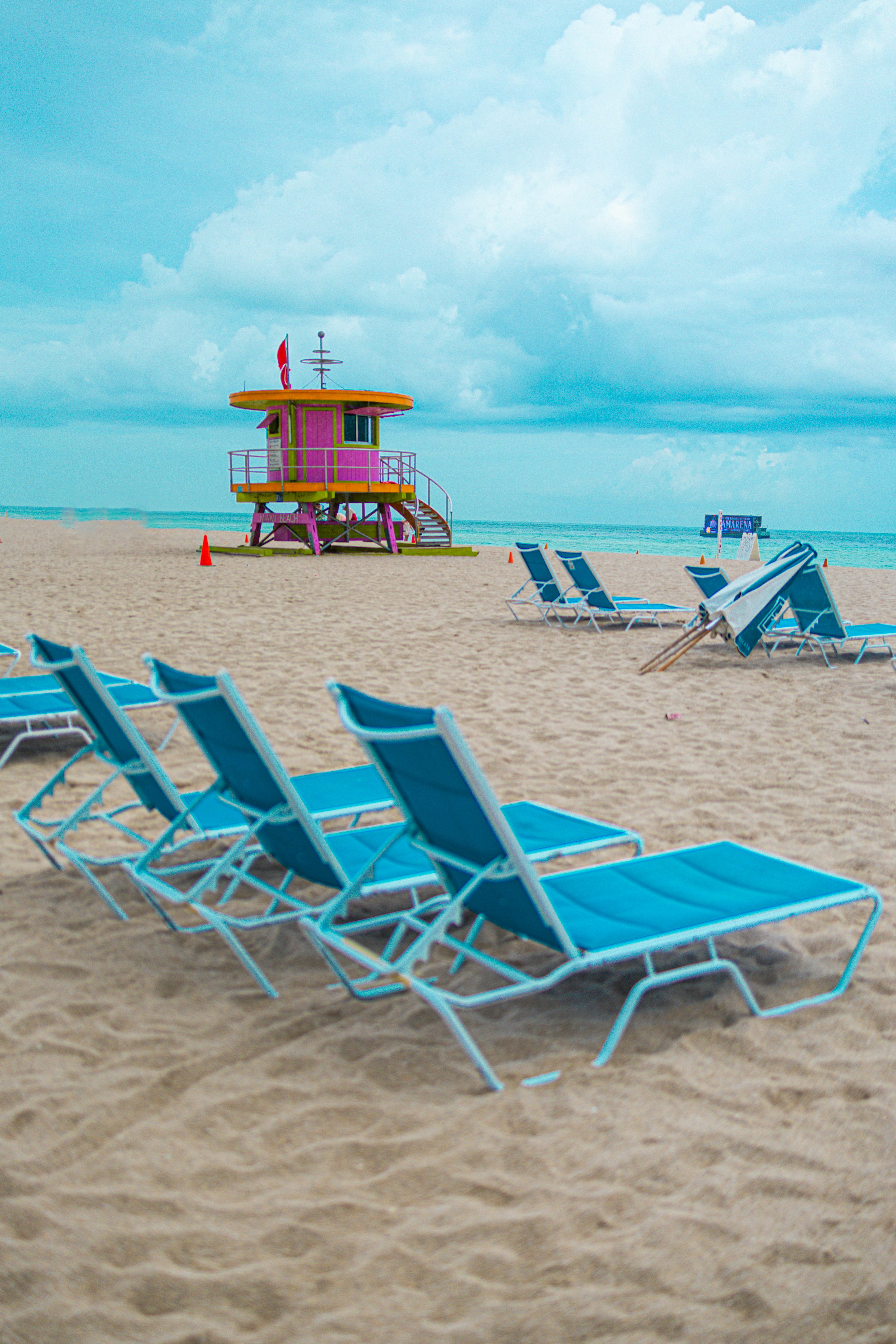 a beach with lounge chairs and a lifeguard tower