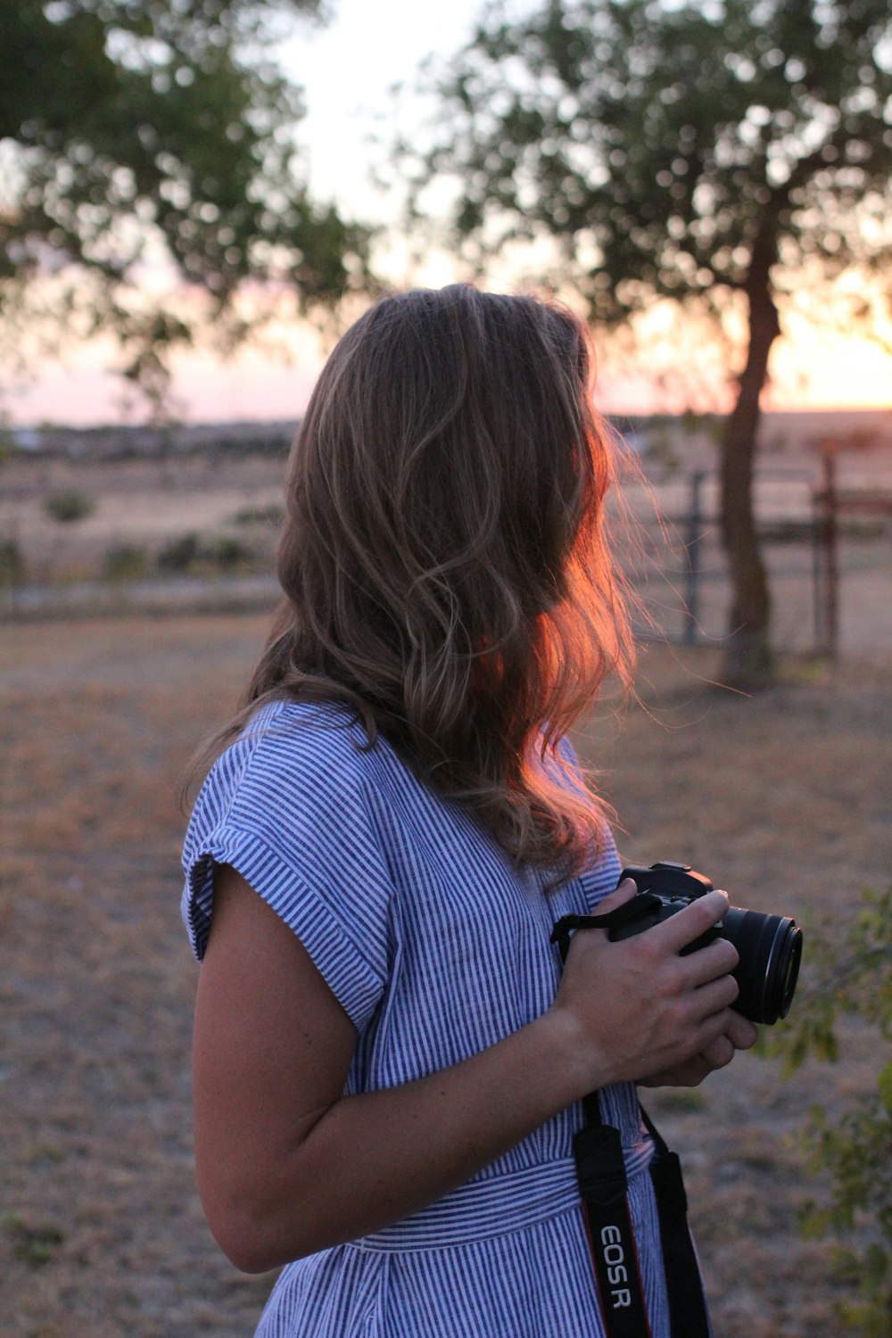 a woman standing in a field holding a camera