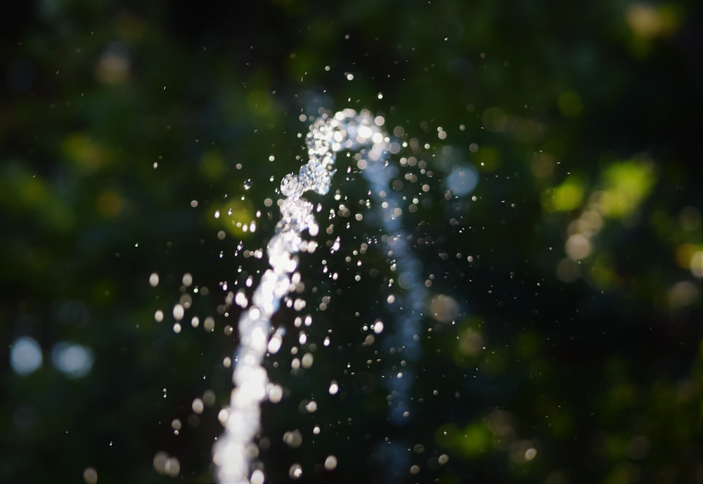 a close up of a water spout with trees in the background