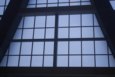 Large, grid-like window structure with several rectangular panes set in a dark metal or concrete frame. The window appears to be part of a tall building, possibly an atrium or a commercial space.