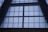 Large, grid-like window structure with several rectangular panes set in a dark metal or concrete frame. The window appears to be part of a tall building, possibly an atrium or a commercial space.