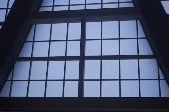 Large, grid-like window structure with several rectangular panes set in a dark metal or concrete frame. The window appears to be part of a tall building, possibly an atrium or a commercial space.