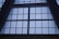 Large, grid-like window structure with several rectangular panes set in a dark metal or concrete frame. The window appears to be part of a tall building, possibly an atrium or a commercial space.