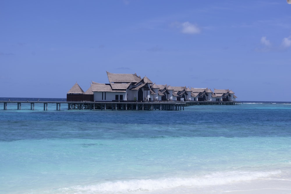 a row of houses sitting on top of a pier next to the ocean