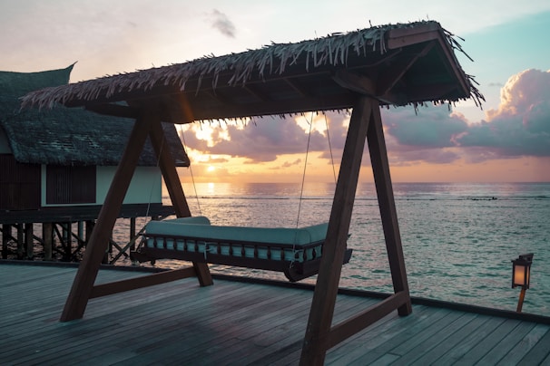 Cozy beachfront bungalow with wooden deck overlooking turquoise waters at sunset.