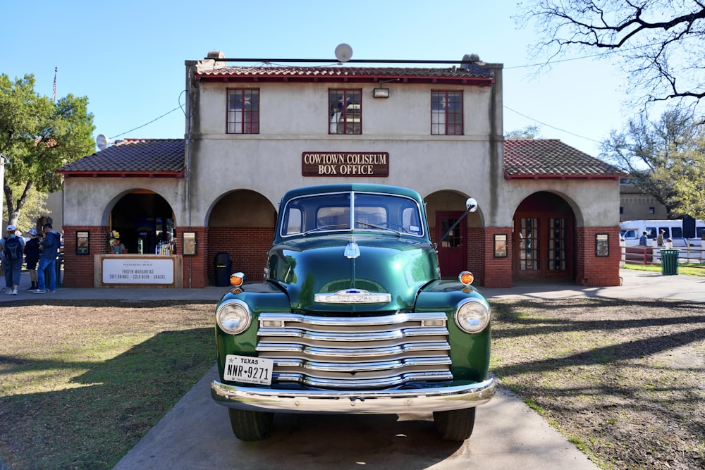 a green truck parked in front of a building