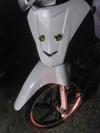A close-up of a motorcycle front, with an arrangement on the front panel that resembles a smiling face. The headlights resemble eyes, and the design below looks like a mouth, giving the image a playful character.