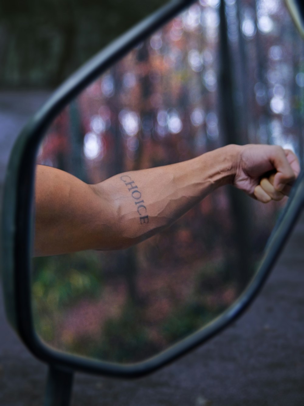 El brazo de una persona se refleja en el espejo retrovisor lateral de un automóvil