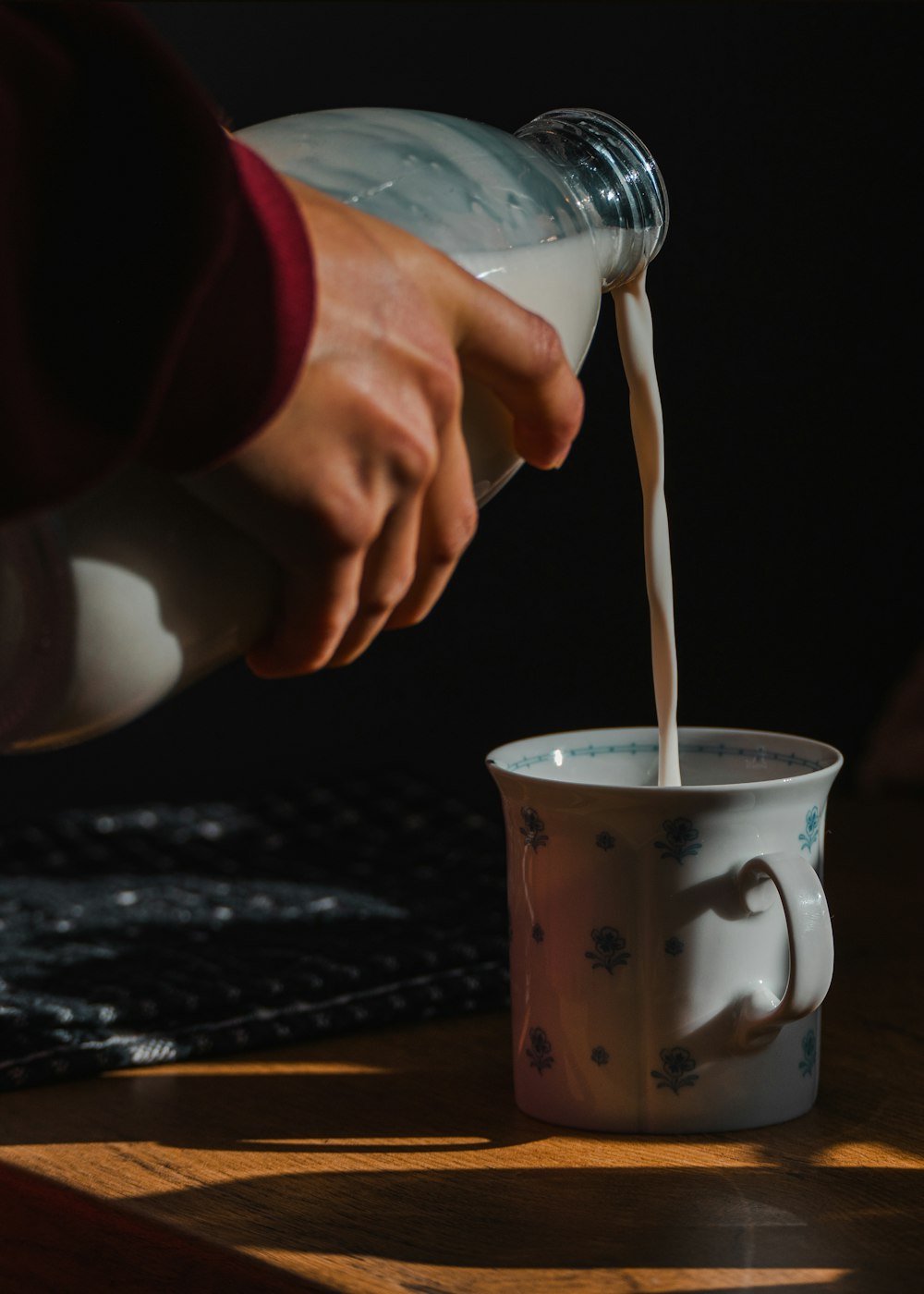 a person pouring milk into a coffee cup