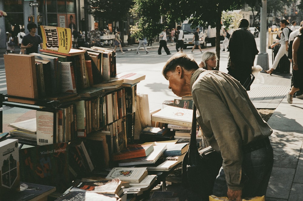 a man looking at books on a sidewalk