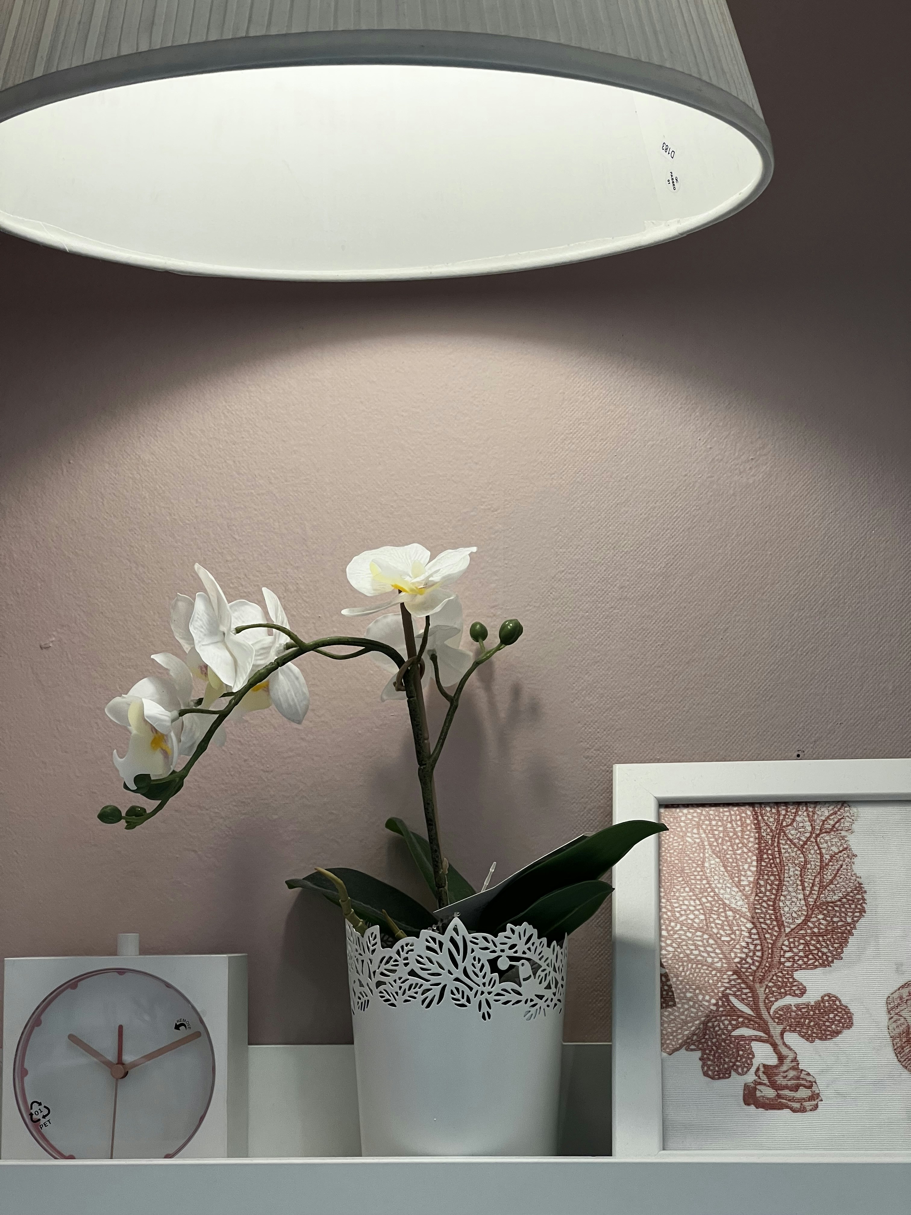 a vase with flowers and a clock on a shelf
