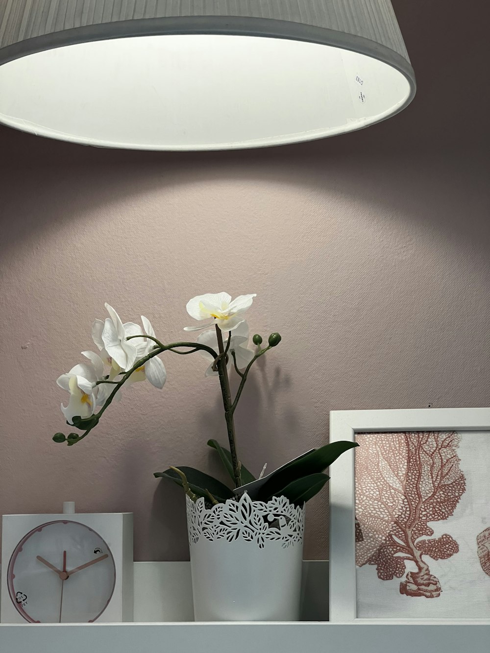 a vase with flowers and a clock on a shelf