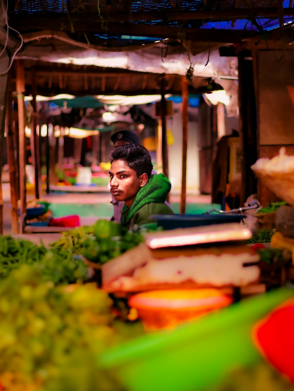 a man sitting in front of a pile of vegetables