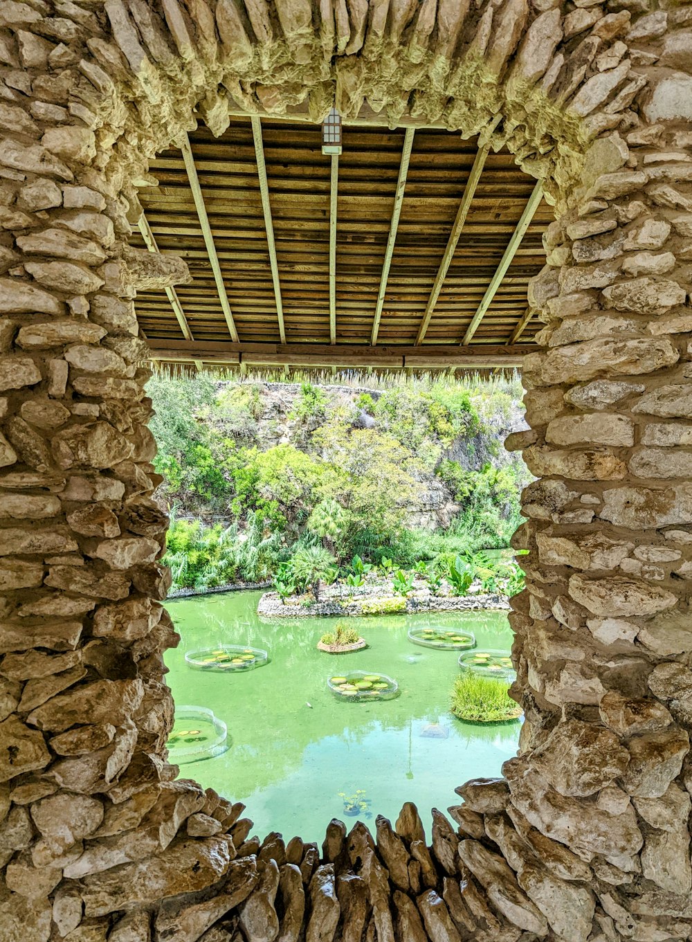 a view of a pond through a stone wall