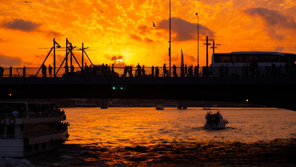 Un grupo de barcos flotando en la cima de un río bajo una puesta de sol