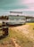 A mobile bar labeled 'Camping Bar' is set up on a grassy area near a body of water. The bar is positioned with a small overhead sign and surrounded by several black barrels with yellow labels. A shaded walkway and some structures can be seen in the distance under a clear blue sky.