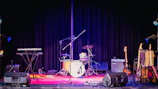 Close-up of guitar and drums during a rooftop corporate event, highlighting the electric 5-piece lineup.