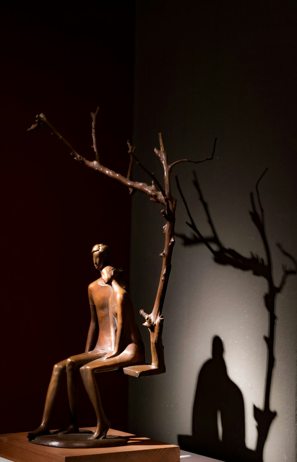 a sculpture of a man sitting on a chair next to a tree
