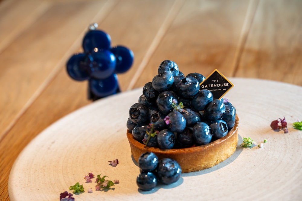 Ein Heidelbeerdessert auf einem weißen Teller auf einem Holztisch