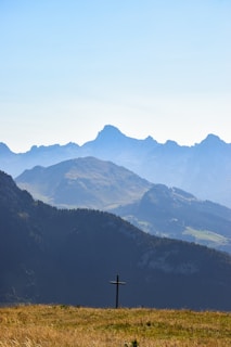 A serene landscape with a sunrise illuminating a cross on a hill, symbolizing hope and faith.